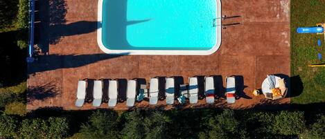 An aerial view of a swimming pool with lounge chairs and a small boat.