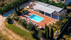 Vue aérienne d’une maison dotée d’une piscine, d’un espace salon extérieur et d’un patio couvert.