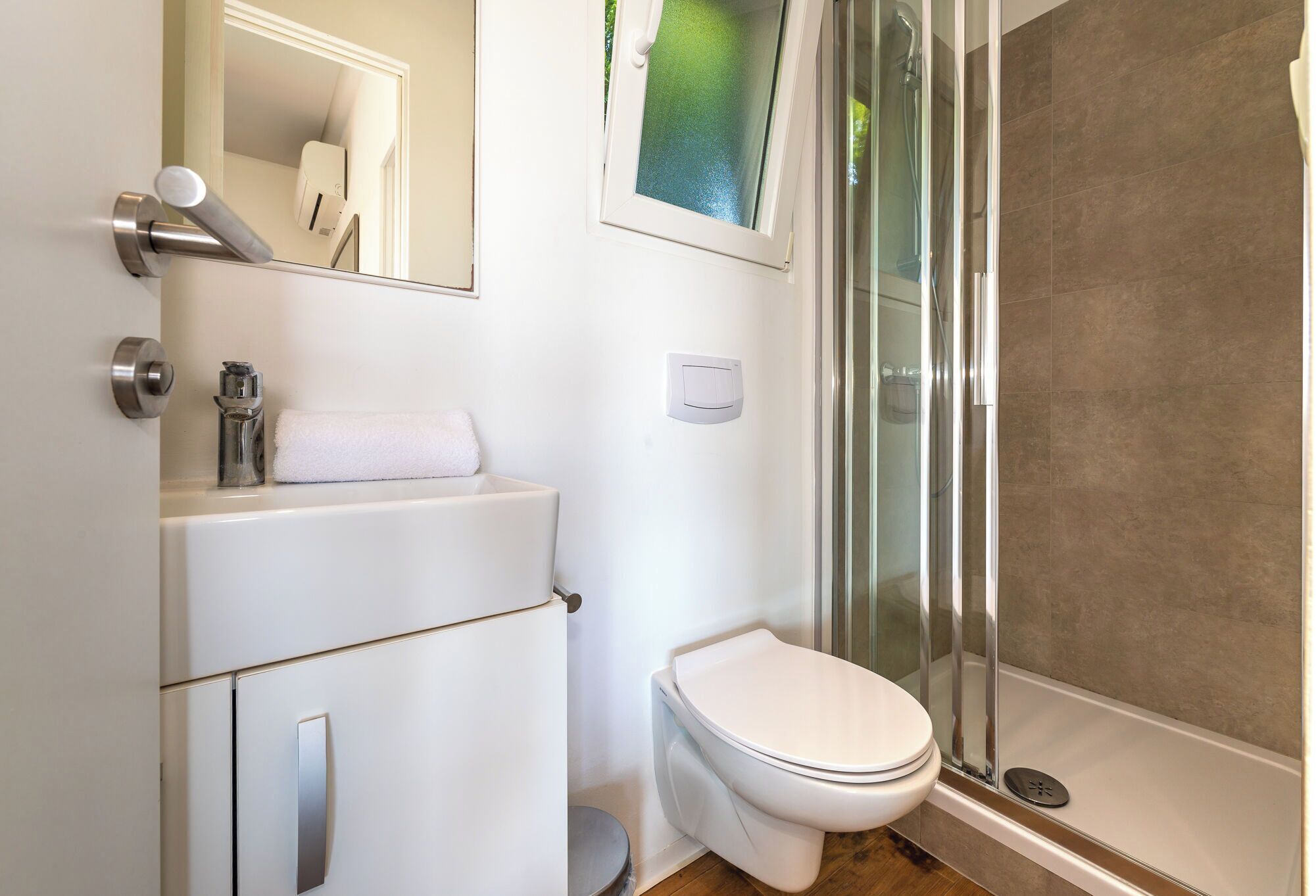 A modern bathroom with a toilet, sink, and glass shower enclosure.