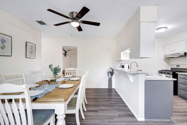 A modern kitchen with white cabinetry, a central island, and a ceiling fan.