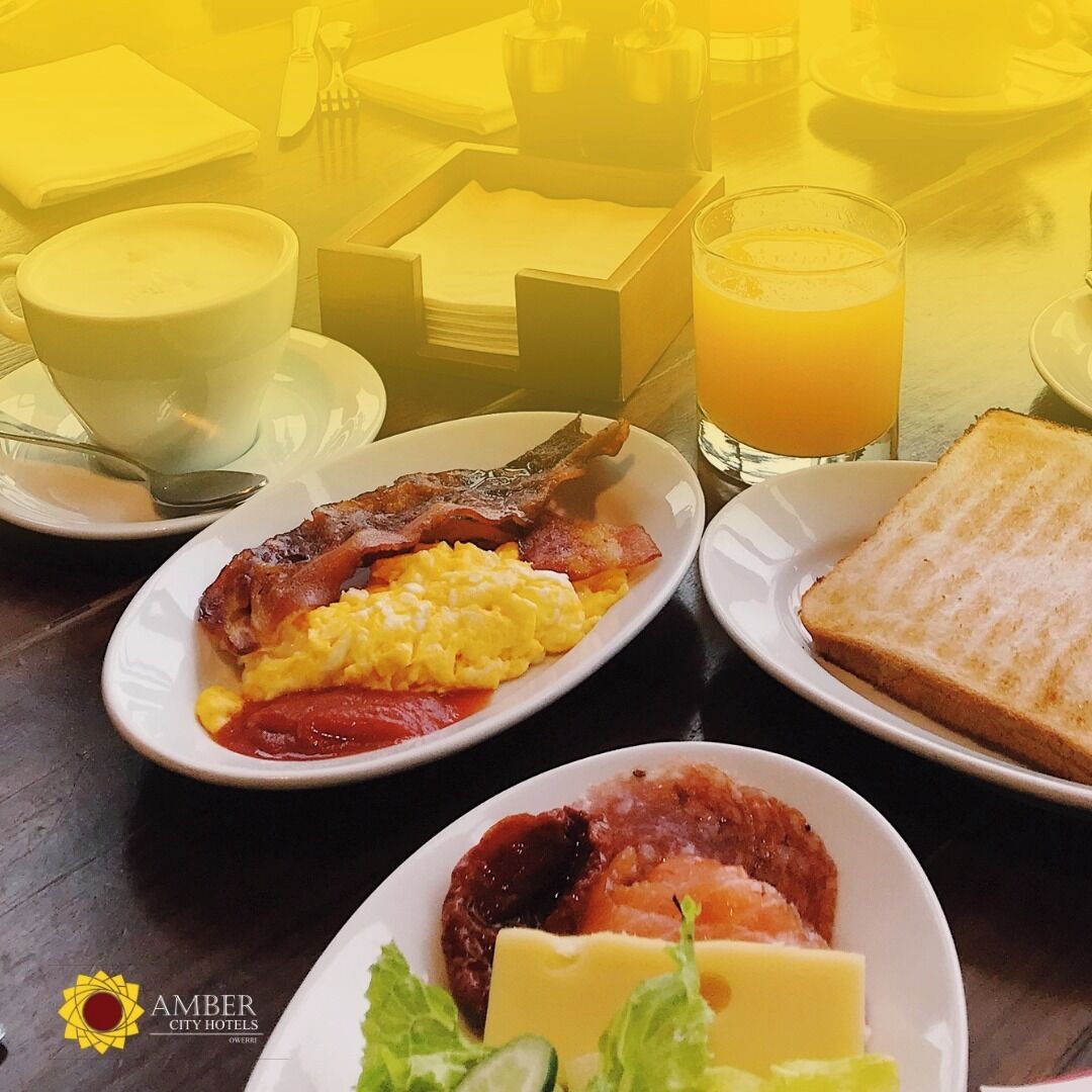 A breakfast setting with plates of eggs, bacon, toast, and a bowl of soup.