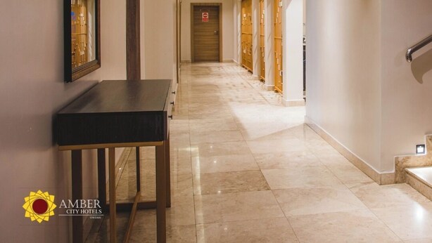 Um corredor de hotel com um longo lance, uma recepção e uma escadaria.