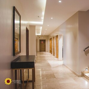 A hotel corridor with a long hallway, a reception desk, and a staircase. - Amber City Hotels (Owerri)