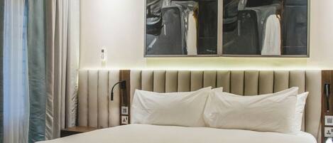 A hotel room with a large bed, a nightstand, a wall-mounted artwork, and a window with curtains.