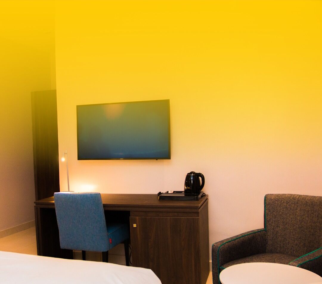 A hotel room with a bed, a desk, a chair, a television, and a coffee maker.