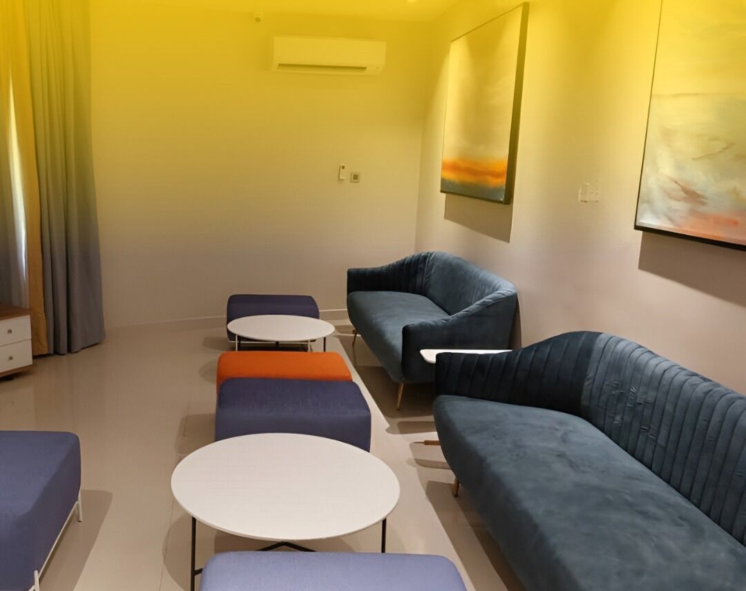 Ein modernes Wohnzimmer mit einer Couch, Hocker und runden Tischen.