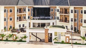 Um hotel com vários andares, entrada destacada, varandas e área de estacionamento.