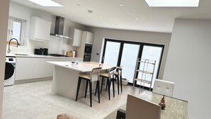 Une cuisine moderne dotée d’un îlot central, d’un coin repas avec des chaises et d’une vue sur l’extérieur.