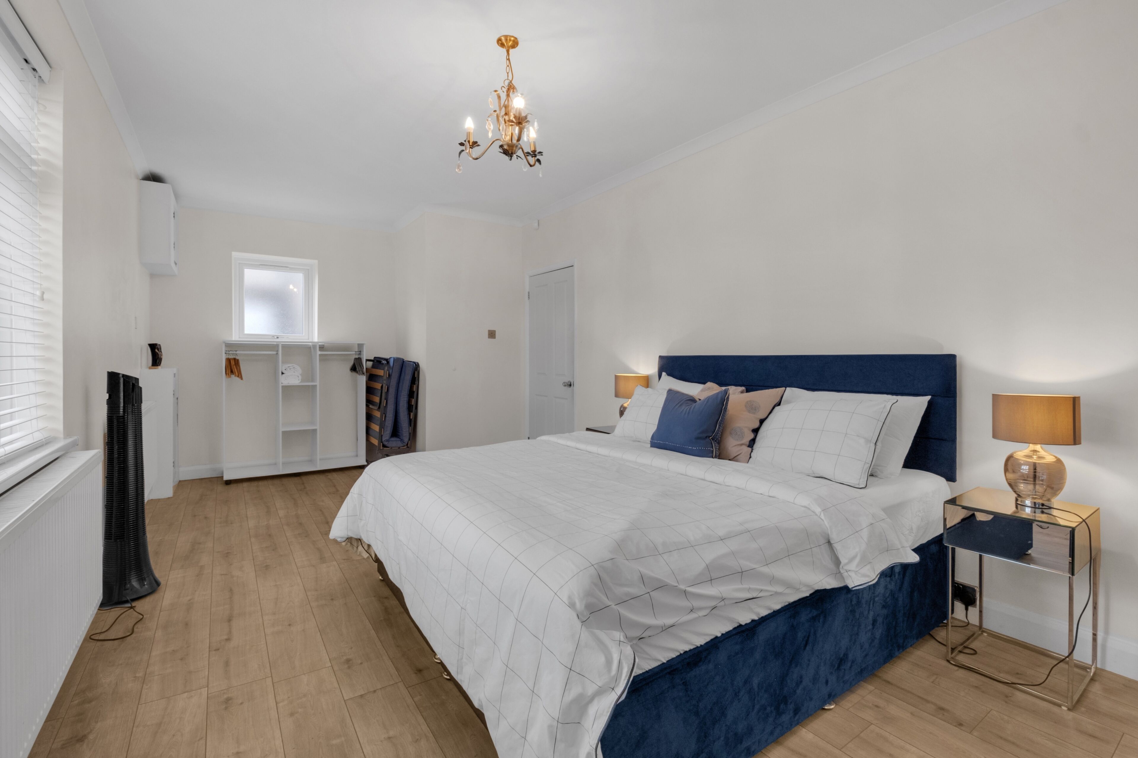 Une chambre à coucher avec un grand lit, un lustre, une armoire et une fenêtre.