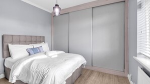 Une chambre à coucher avec un lit, une tête de lit, une suspension et une porte coulissante.