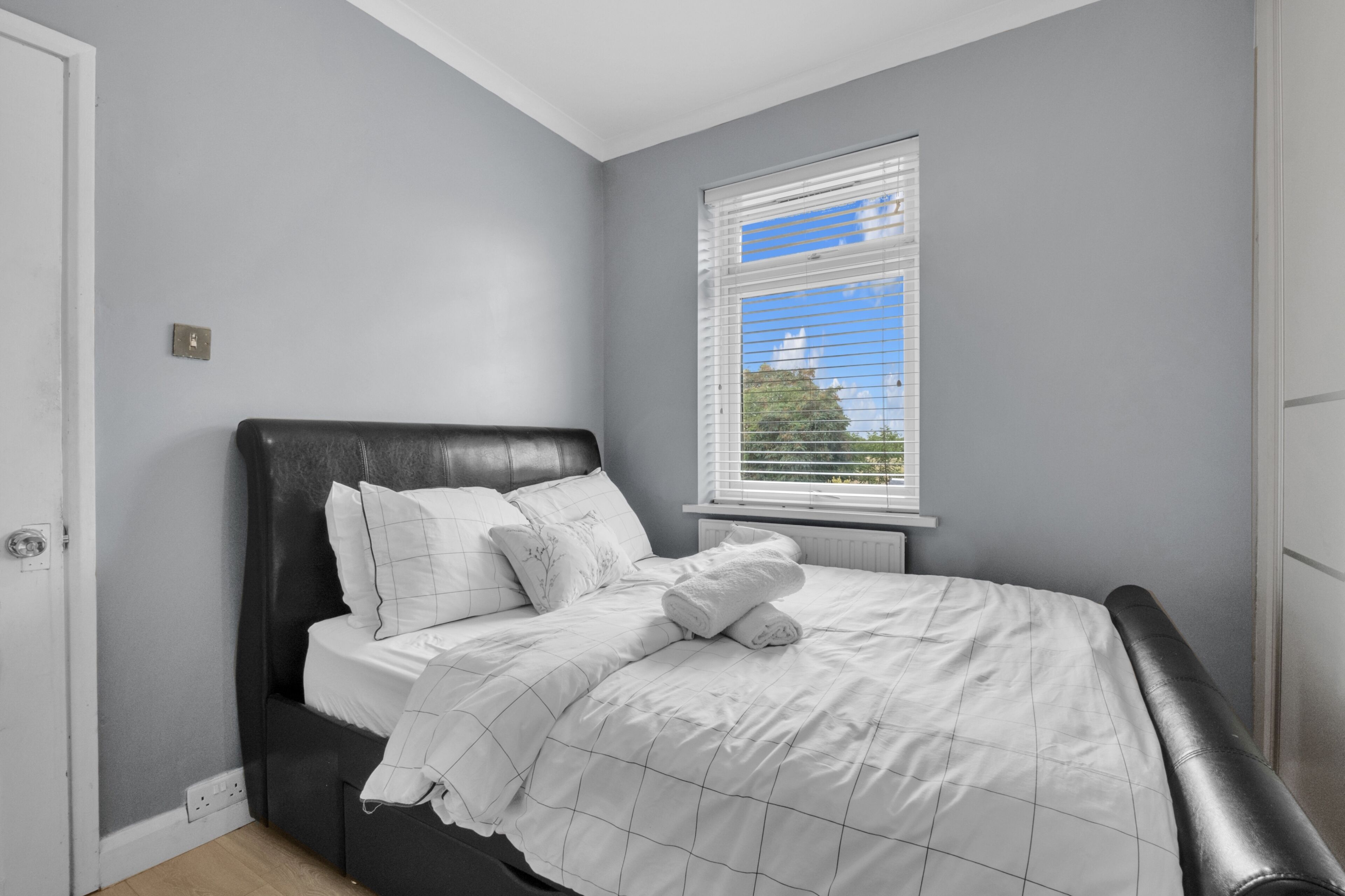 Un dormitorio con cama, ventana y puerta.