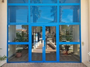 Enter a tranquil oasis with large glass doors offering a glimpse into the interior, surrounded by lush greenery.