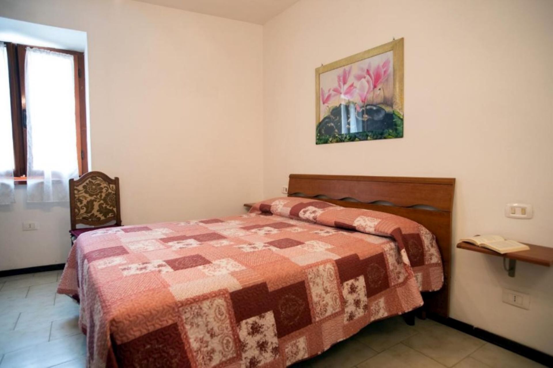 Une chambre à coucher avec un lit, une tête de lit en bois, une table de chevet, un tableau et une fenêtre.