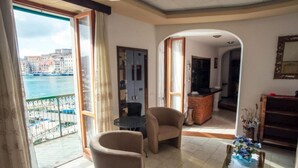 A spacious living room with a view of the sea, a balcony with a railing, and a kitchen area. - Apartment Il Veliero with Amazing Sea View (Portoferraio)