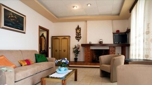 A living room with a sofa, armchairs, a coffee table, a fireplace, and a television. - Apartment Il Veliero with Amazing Sea View (Portoferraio)