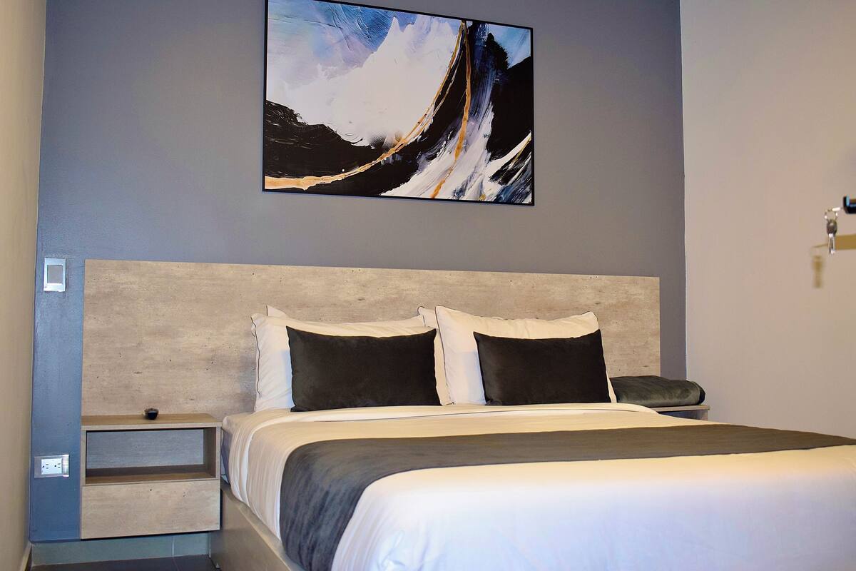 A modern hotel room with a large bed, a headboard, and a nightstand.