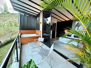 Un patio moderno al aire libre con una mesa y sillas de vidrio, un banco de madera y vistas del paisaje circundante.