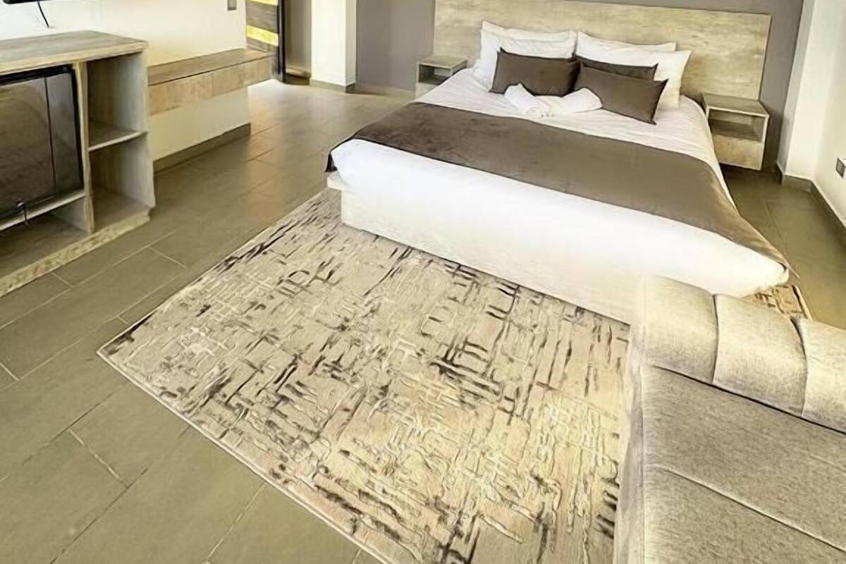 A modern bedroom with a large bed, a flat-screen TV, and a minimalist decor.