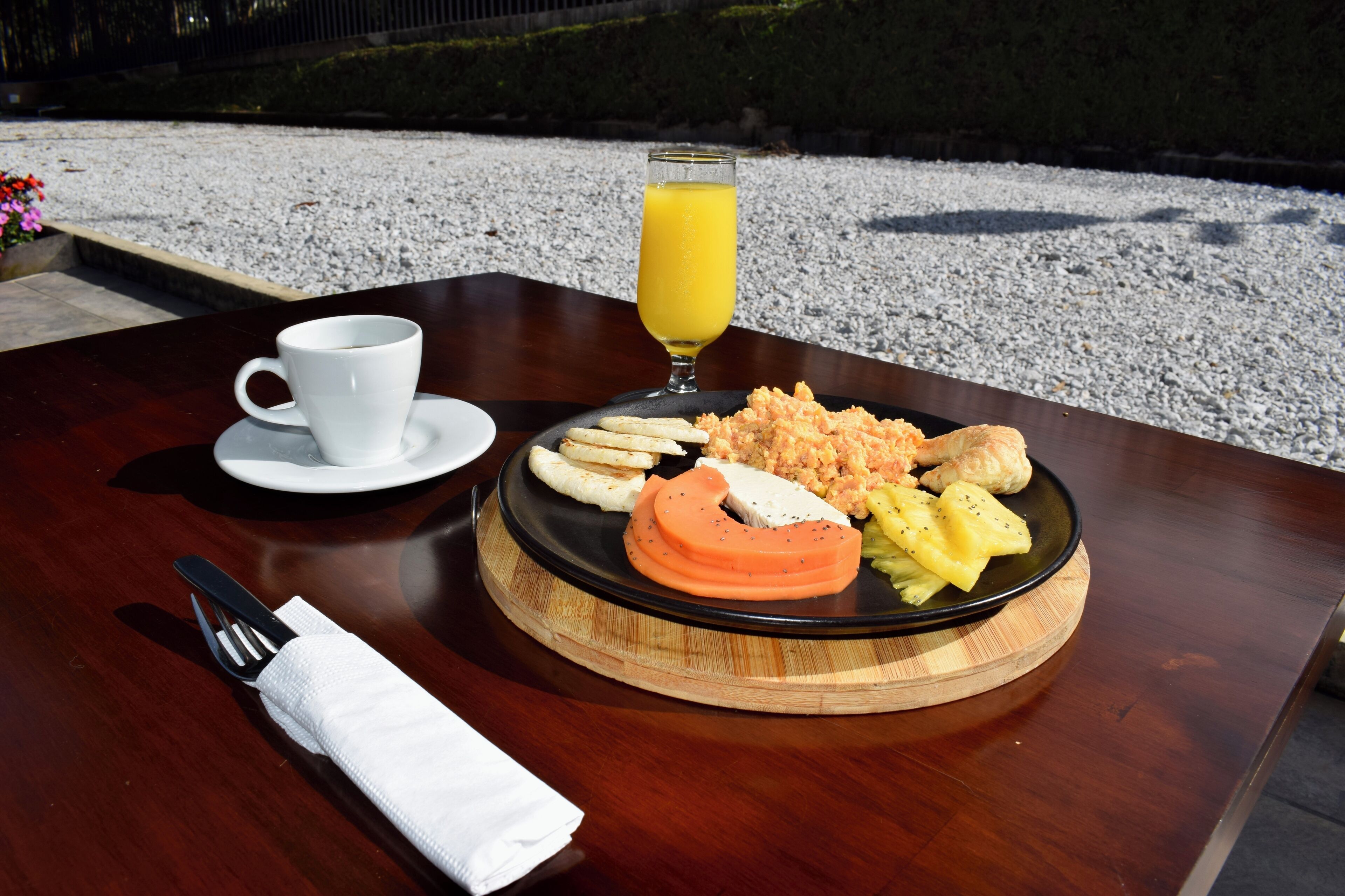 A breakfast setting with a plate of food, a glass of orange juice, and a cup on a wooden table.