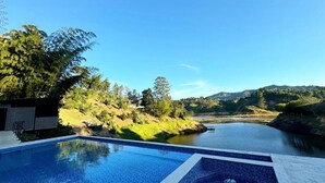 A swimming pool with a view of a river and hills. - Rooca Guatape (El Peñol)