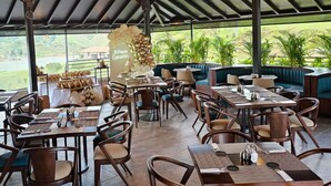An outdoor restaurant with round tables and chairs, a decorative balloon arch, and a view of greenery. - Rooca Guatape (El Peñol)