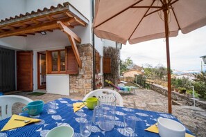 An outdoor dining area with a table set for two, a stone wall, and a view of the surrounding landscape. - Apartment I Pini with a view of the gulf (Portoferraio)