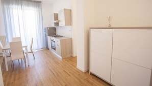 A modern kitchen with a dining area, wooden cabinets, and a white countertop. - Anna Apartment just a few minutes from the centre (Portoferraio)