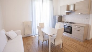 A modern kitchen with a dining table and chairs, a built-in oven, and a stove. - Anna Apartment just a few minutes from the centre (Portoferraio)