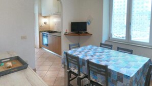 Eine kompakte Küche mit Herd, Backofen und einer kleinen Essecke mit Tisch und Stühlen.
