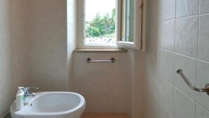 Ein kleines Badezimmer mit Toilette, Bidet und einem Fenster.