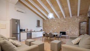 Un salon moderne avec un mur en pierre, un coin cuisine et un espace repas.