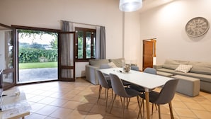 Un salon moderne comprenant un coin repas, un canapé et une grande fenêtre donnant sur un paysage verdoyant.