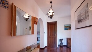 Un couloir avec une coiffeuse à plateau en verre, une porte en bois et un tableau encadré accroché au mur.