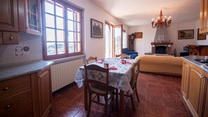 Une cuisine chaleureuse avec des meubles de rangement en bois, une table à manger avec des chaises, un lustre et une cheminée.
