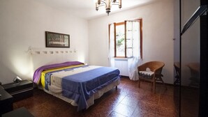A bedroom with a bed, a chair, a window, and a chandelier. - Three-room apartment Villa Paola in Rio Marina (Rio Marina)