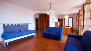 A room with a bed, two sofas, a wooden wardrobe, and a dining area. - Four-room apartment  with a view over Rio Marina (Rio Marina)