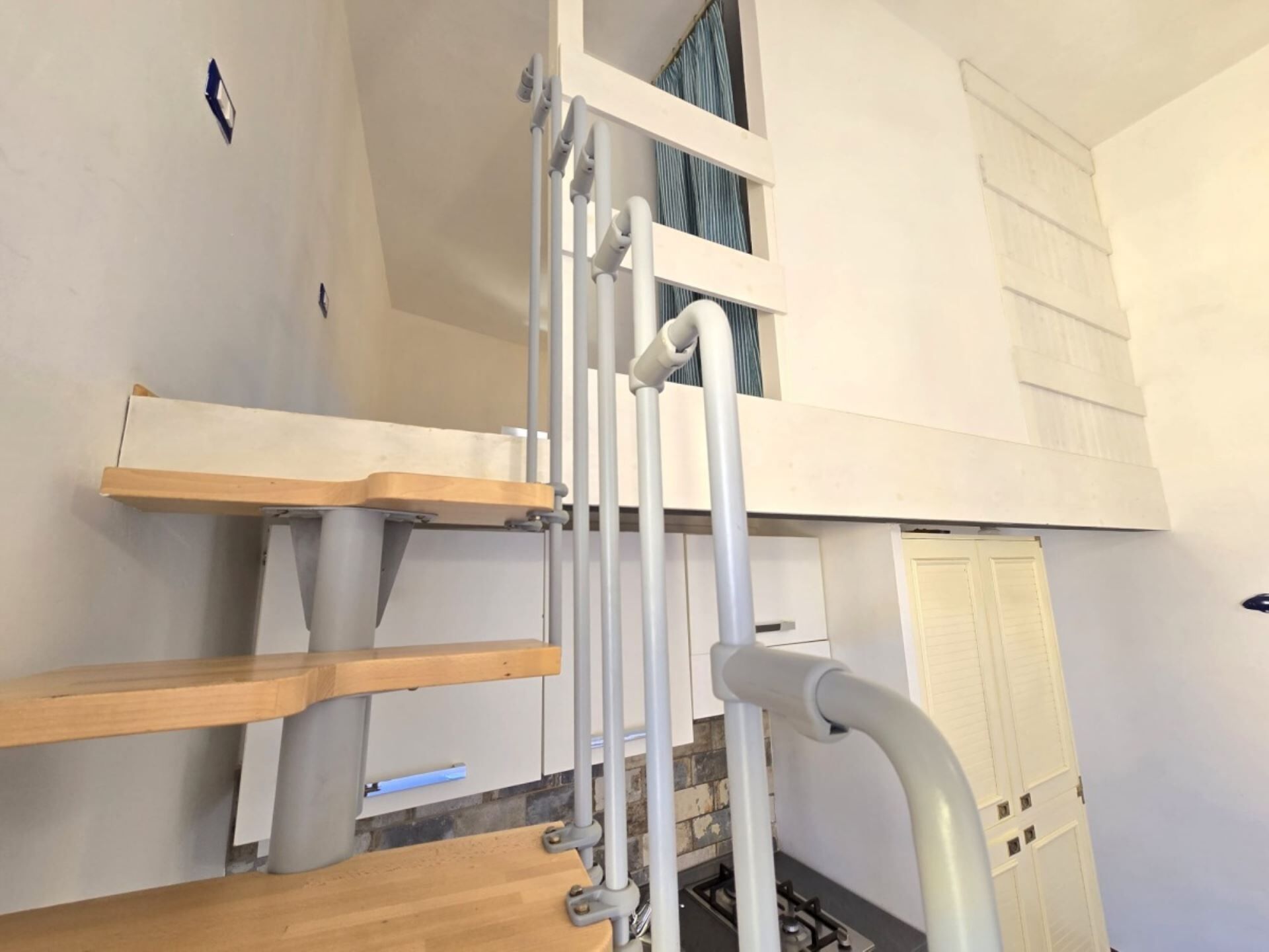 Eine Treppe mit Holzstufen und Metallgeländern, die zu einer höheren Etage führt.