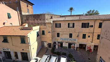Vista di una strada con un edificio con la scritta "PANIFICIO" e "PORTOFRANCO AMBIENTE", auto parcheggiate e un cielo azzurro intenso.