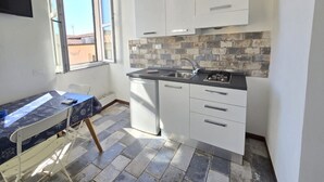 Cocina compacta con armarios blancos, salpicadero de azulejos y ventana que proporciona luz natural.