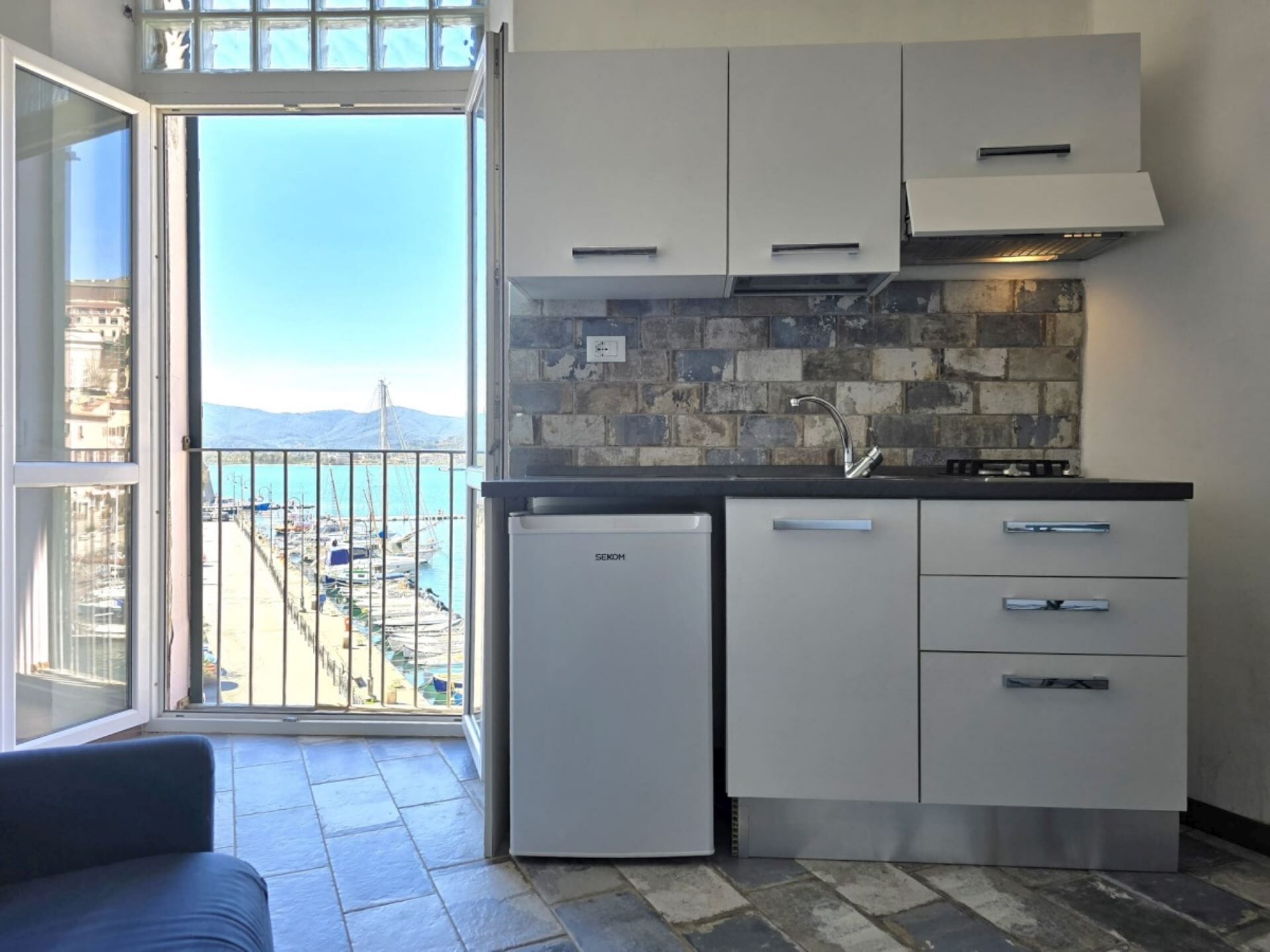 Una cucina compatta con vista sul mare, un frigorifero e un lavello.