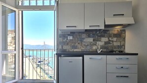 A compact kitchen with a view of the sea, a refrigerator, and a sink.
