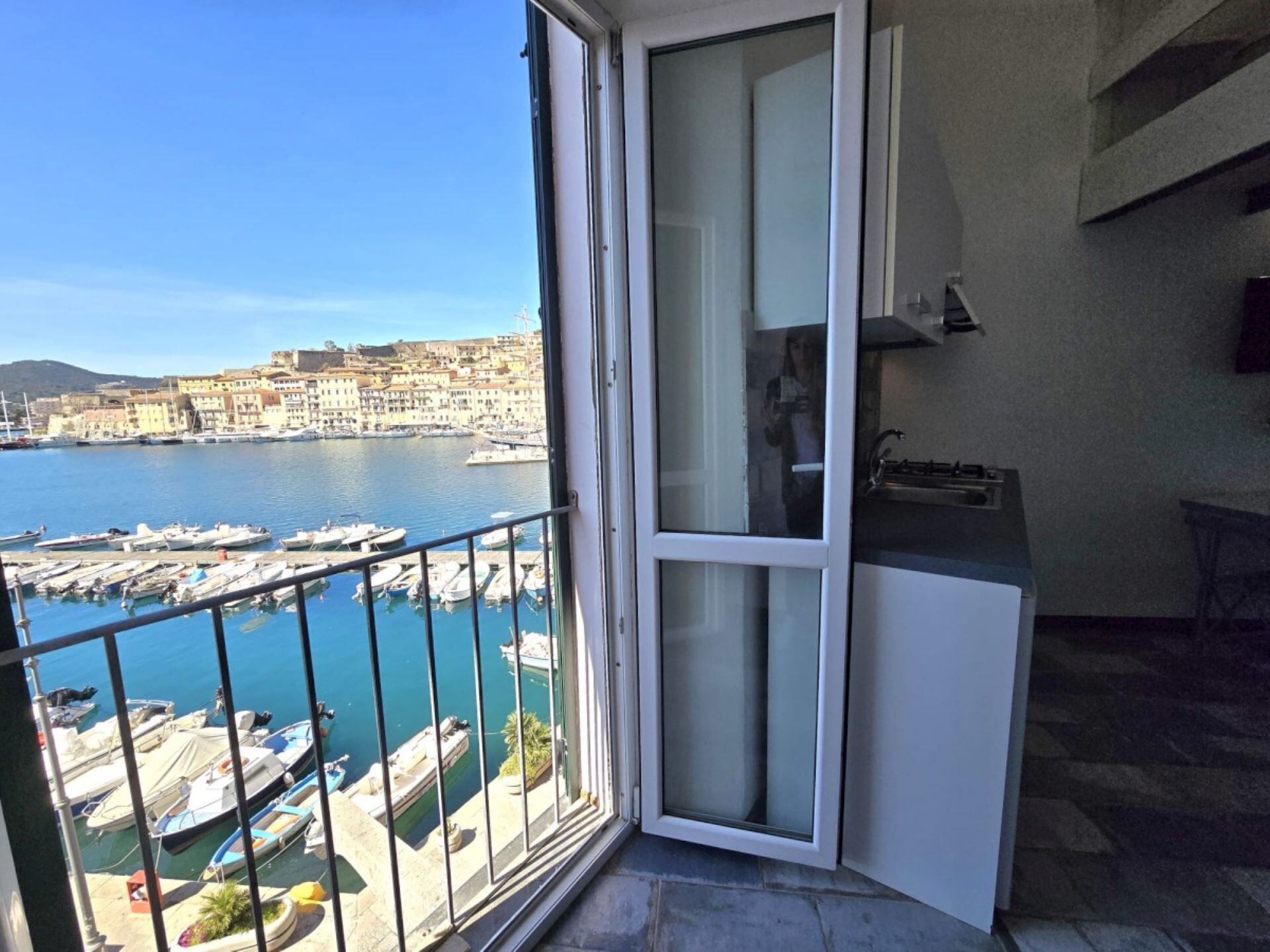 Un balcone con vista su un porto turistico e edifici dall'altra parte dell'acqua.