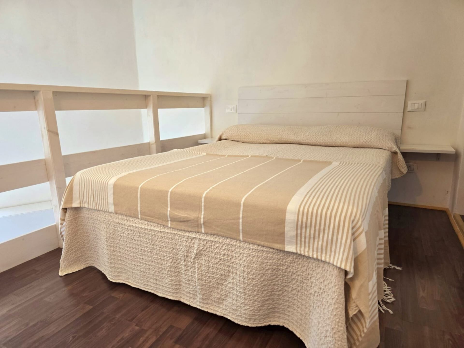 A bedroom with a bed, wooden headboard, and a window with a view.