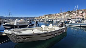 A marina with boats docked, clear blue sky, and buildings in the background.