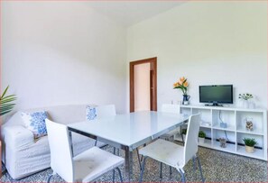 A modern living room with a dining table, white sofa, and TV.