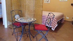A room with a bed, two chairs, a small table, and a decorative partition.