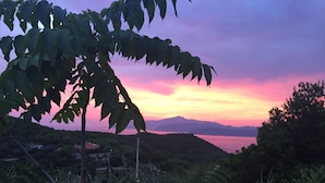 A landscape with a view of mountains and a body of water during sunset.