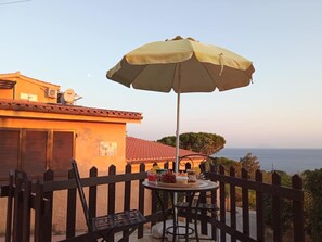 Un balcone con tavolo, sedie e ombrellone.