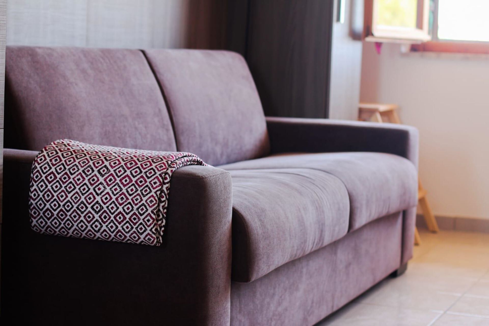 Un salon moderne avec un canapé de couleur foncée et un coussin décoratif à motifs.