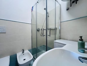 Un baño moderno con ducha de vidrio, lavamanos blanco y bañera.